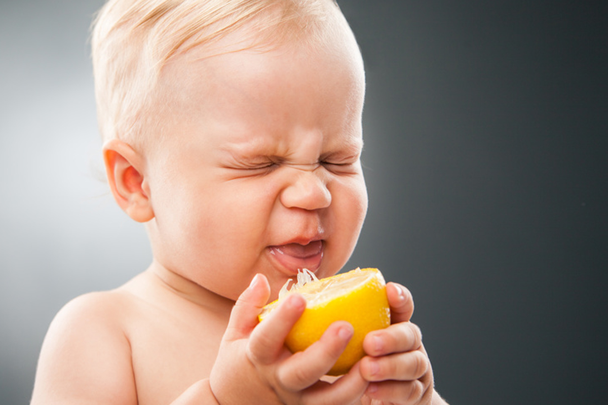 Baby squinting eyes while licking lemon
