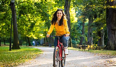 Frau auf einem Fahrrad fährt einen Parkweg entlang