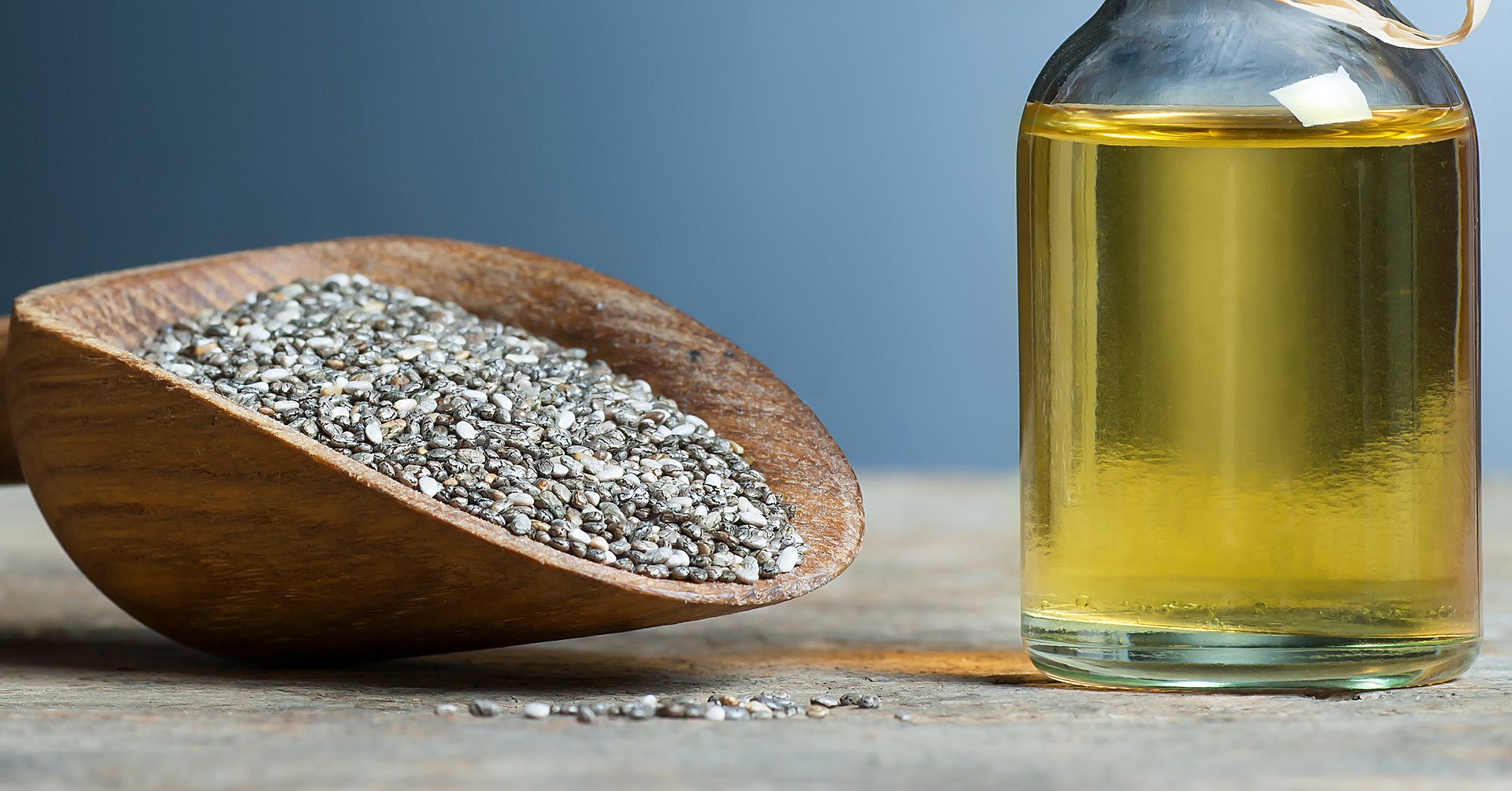 Glass bottle of Chia oil and Chia seeds ( Salvia Hispanica ) in wooden shovel on wooden rustic background. Cereal healthy food contains omega 3, a dietary supplement gluten free Chiasamen und Chiaöl