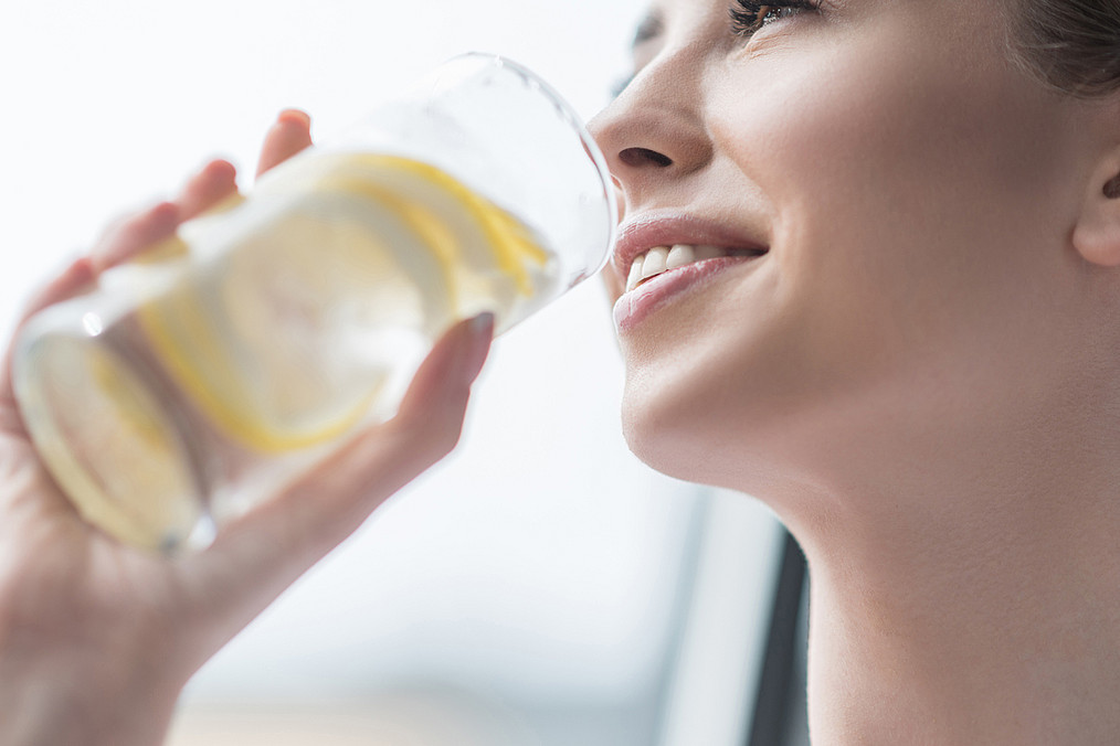 Eine Frau trinkt Wasser aus einem Glas.