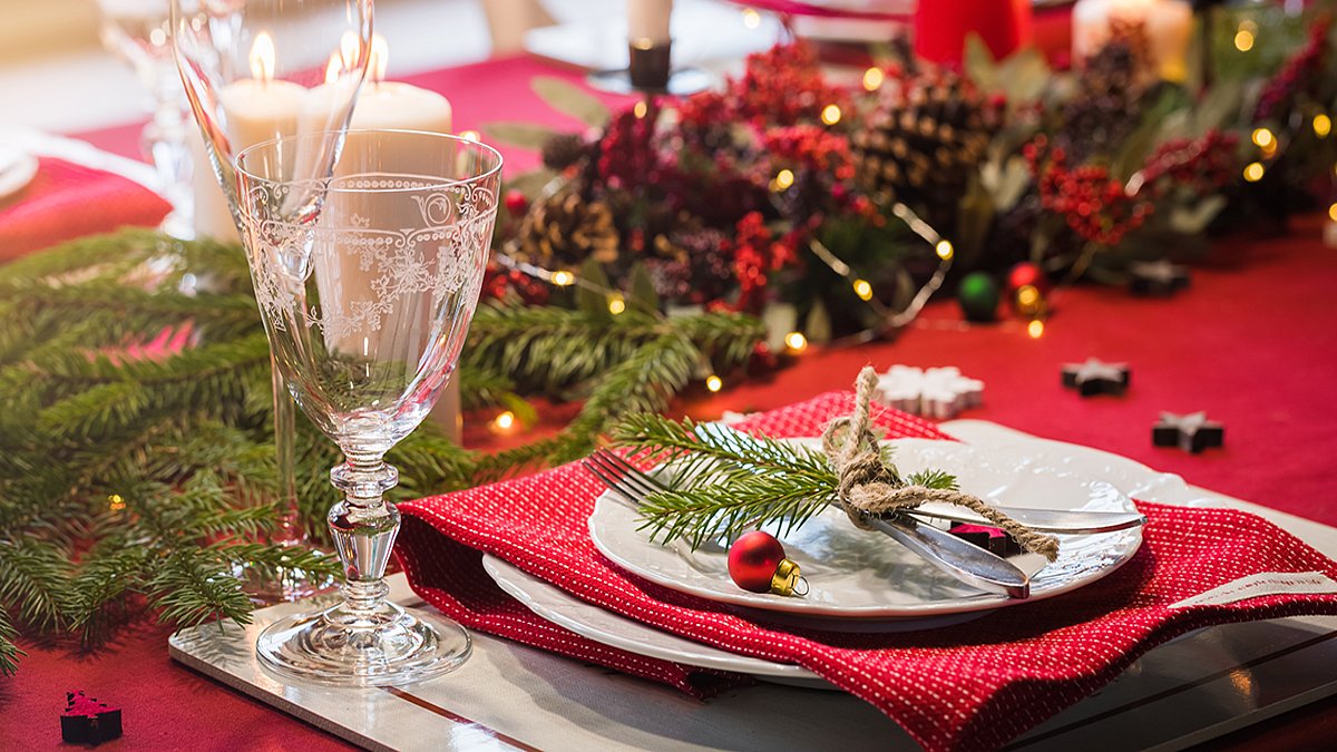 Table served for Christmas dinner, festive setting with decorations, burning candles and fir-tree branches