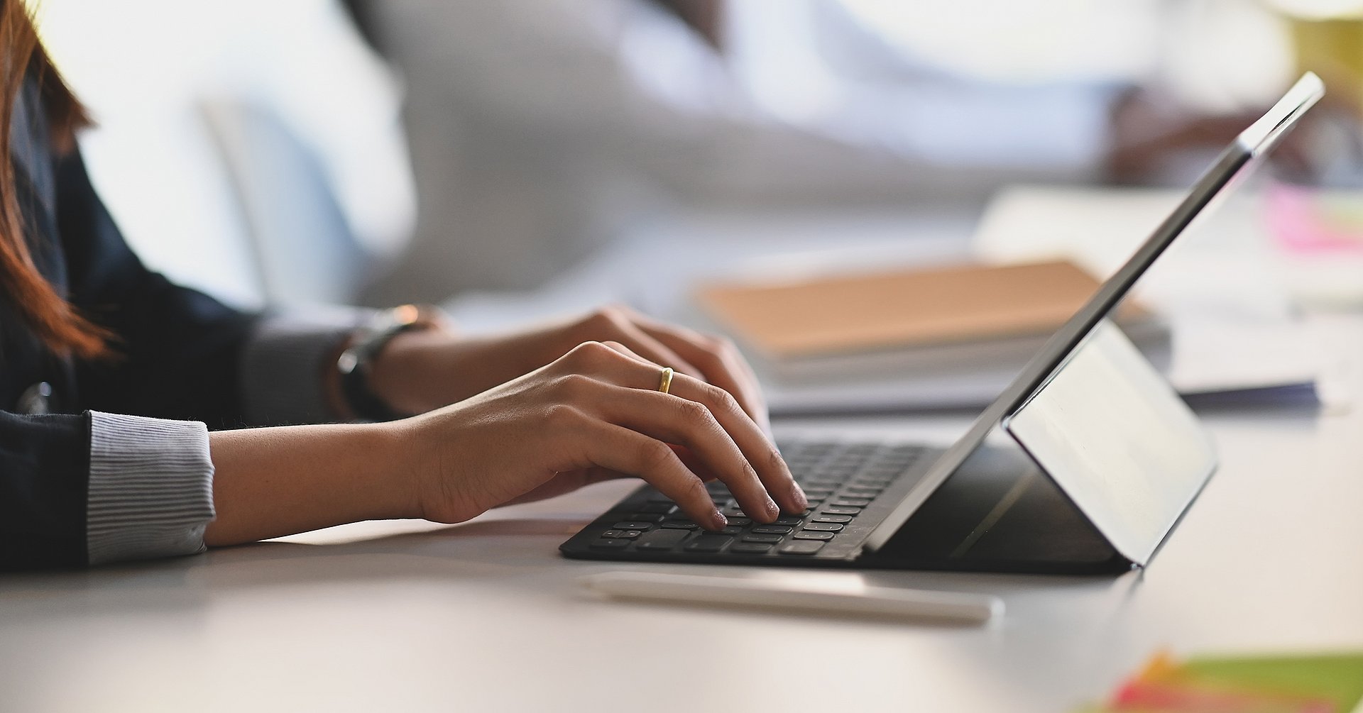 Cropped shot of business woman hand while typing on computer tablet and sitting next to her colleague. Computerarbeit (Symbolbild)