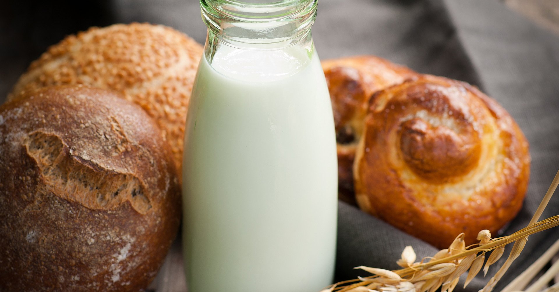Milch und Backwaren verschiedene Brötchen und eine kleine Karaffe mit Milch