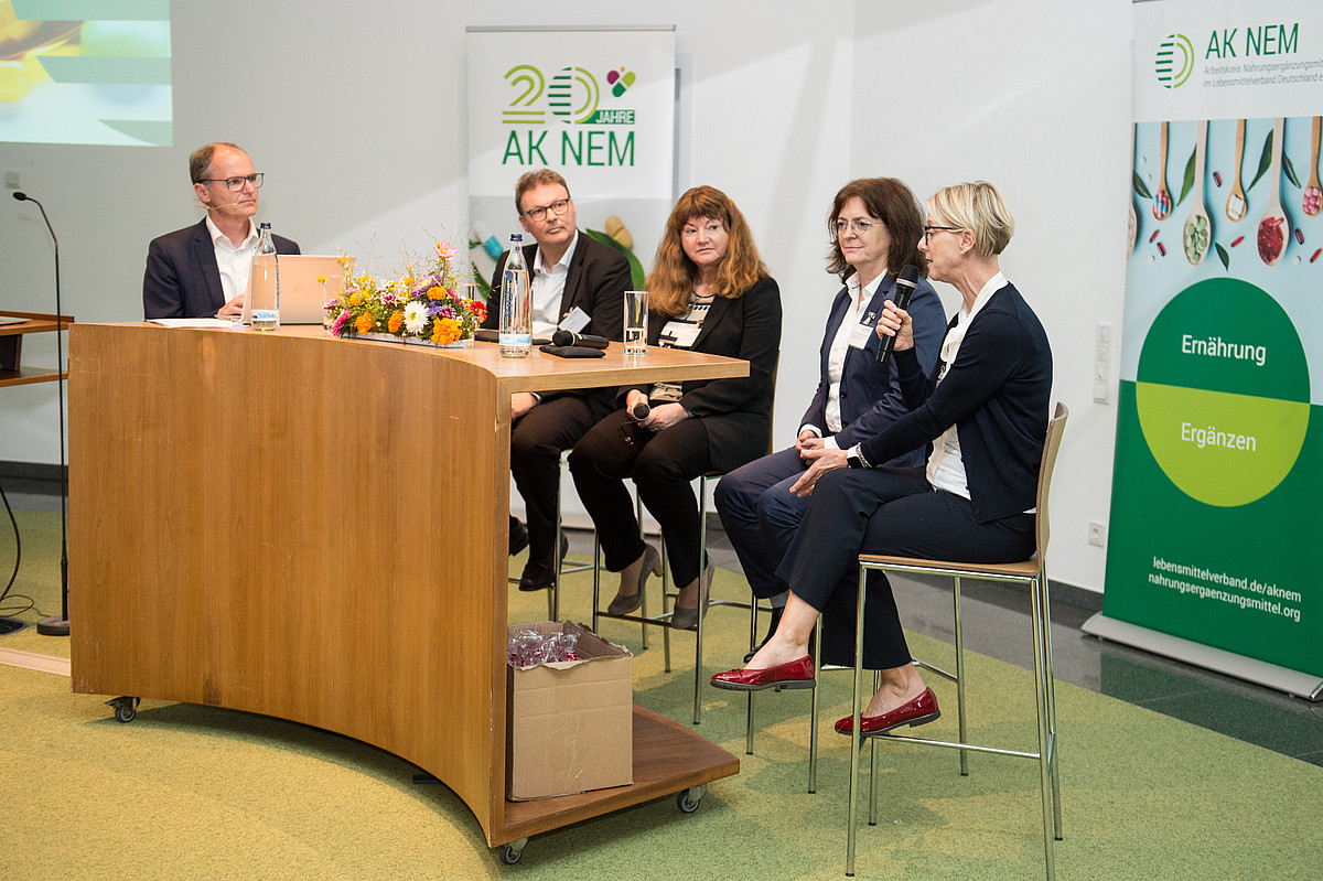 Podiumsdiskussion mit fünf Personen an einer Stehtischbrücke