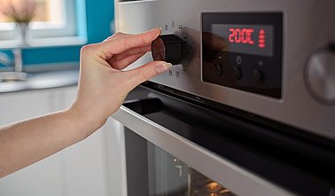 Woman regulates the temperature of the oven
