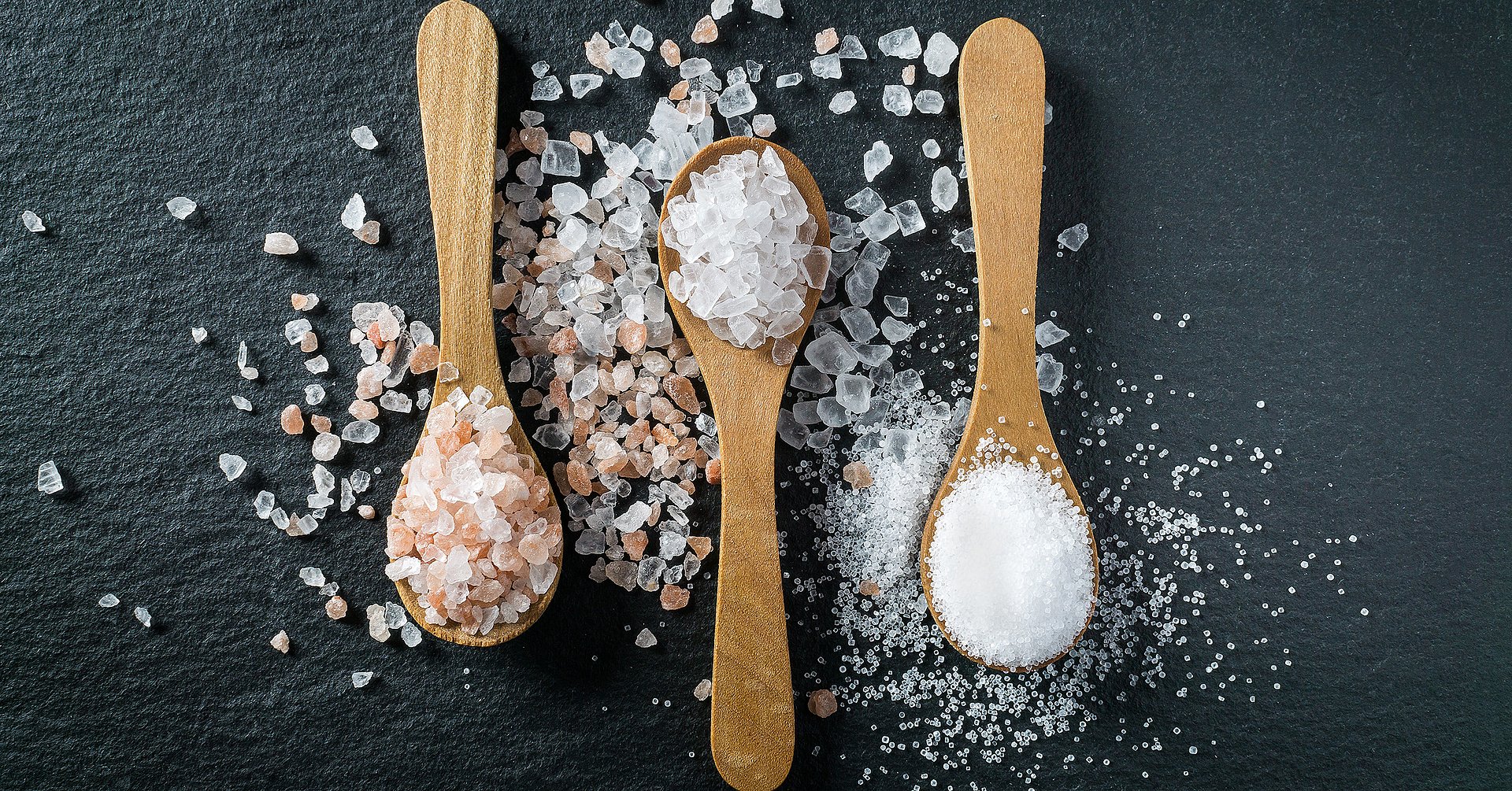 Different types of salt. Top view on three wooden spoons