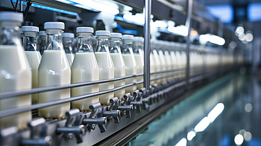 Abfüllen von Milch oder Joghurt in Plastikflaschen auf einem Fließband in einer Fabrik, Konzept mit automatisierter Lebensmittelproduktion.