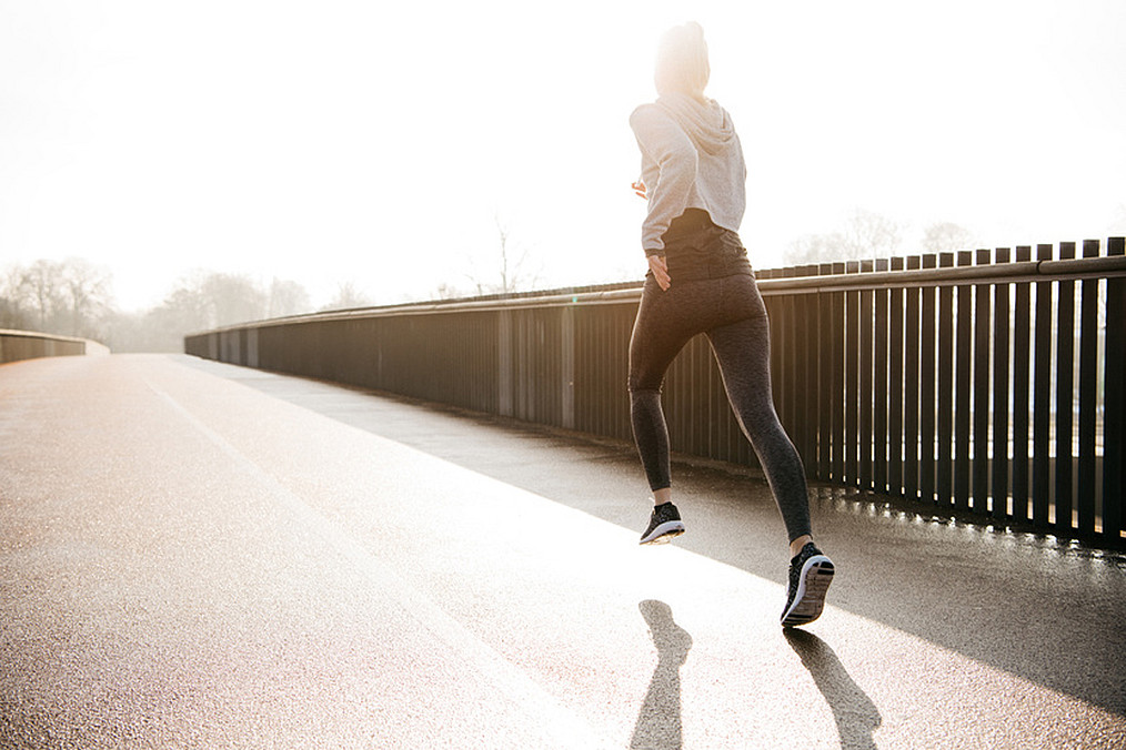 Woman jogging on road in sunny day