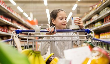girl with food in shopping cart at grocery store
