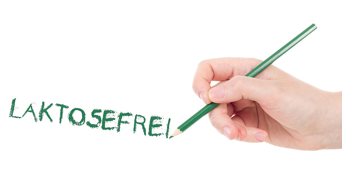 ein Hand hält einen grünen Bleistift und schreibt das Wort Laktosefrei