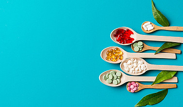 Top view Variety of vitamin and mineral pills in wooden spoon on Colored background. Top view of assorted pharmaceutical medicine pills. Dietary supplement healthcare product