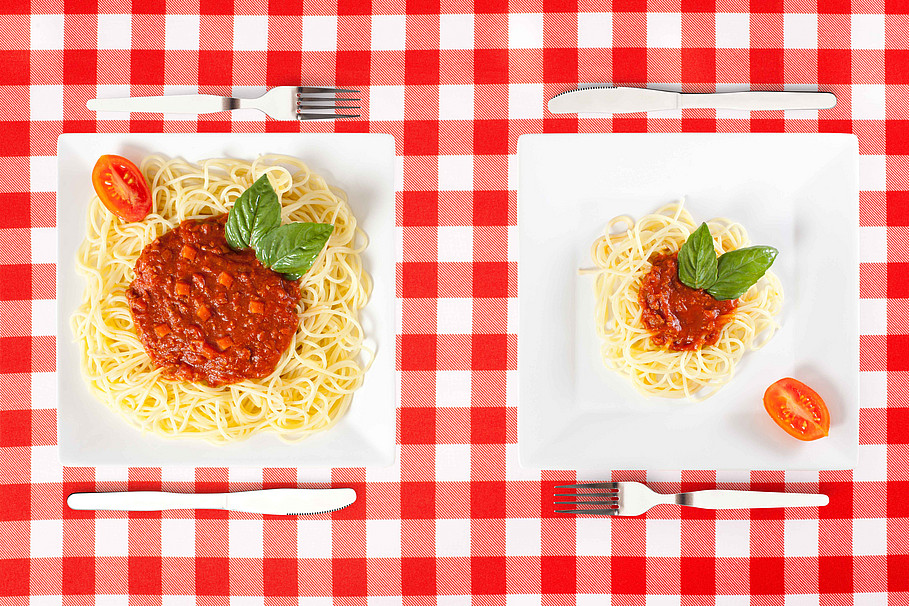 Zwei Teller mit jeweils einer großen und einer kleinen Portion Spaghetti