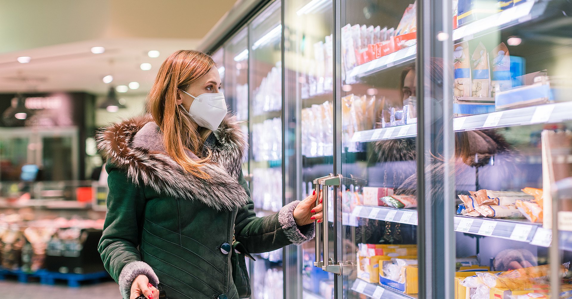 Woman at supermarket freezer section wearing face mask
